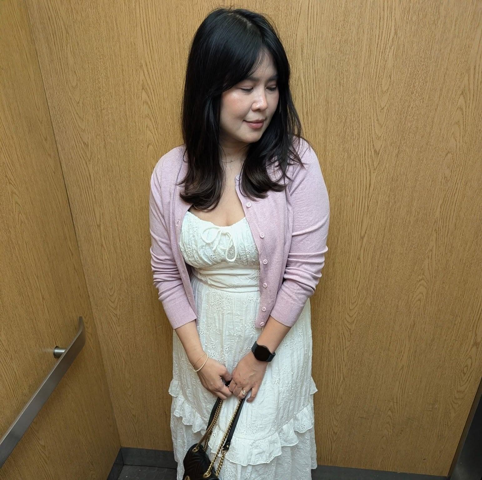 Patt smiling, wearing a pink cardigan