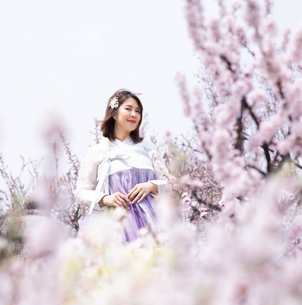 Patt, the artist, standing among blossoming trees